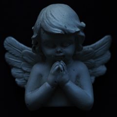 Statuetka modlącego się anioła na czarnym tle
