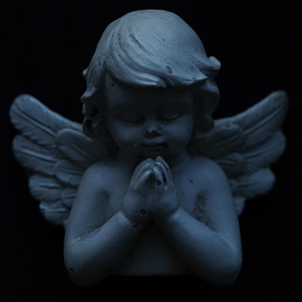 Statuetka modlącego się anioła na czarnym tle